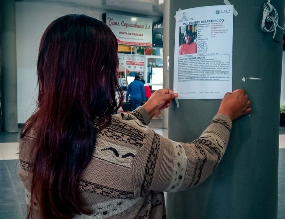 Una mujer pega un letrero de búsqueda en la Nueva Terminal de Buses de Tarija. Foto: Yobana Knaudt
